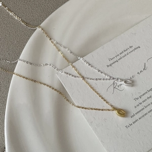 Detailed view of silver and gold U-shaped necklaces on a white ceramic plate