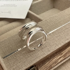 Vue macro de bagues ondulées en argent sterling S925 poli dans un coffret à bijoux en lin beige
