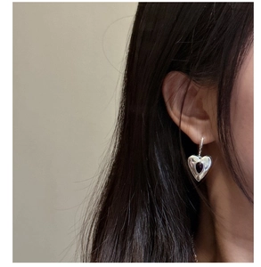 Close-up of S925 silver heart earring with black onyx stone worn on a female ear