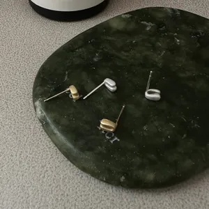 Vue détaillée de boucles d'oreilles mates dorées et argentées sur un plateau en pierre