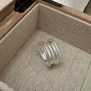 Vue détaillée d'une bague multicouche en argent torsadé dans un écrin en bois