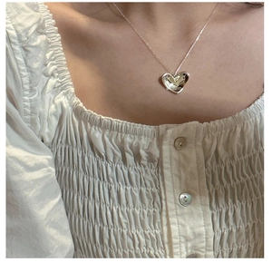 Polished silver heart pendant necklace on model with elegant white shirt