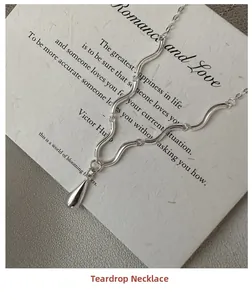 Vue détaillée du collier goutte d'argent avec chaîne ondulée sur une carte décorative