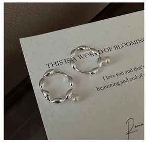 Macro detail of S925 silver twisted hoop earrings with elegant white pearl accents