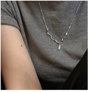 Gros plan du collier en argent S925 à vagues avec pendentif goutte sur un haut gris