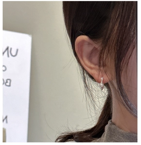 Close-up of a minimalist S925 sterling silver hoop earring with a white pearl on an ear