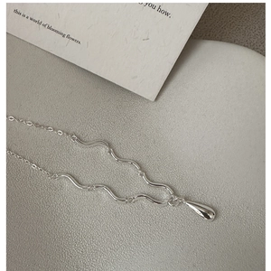 Vue macro du pendentif goutte d'argent avec chaîne à maillons texturés ondulés