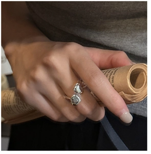 Detail of silver double heart open ring worn by model holding a newspaper