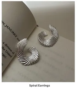 Detailed close-up of S925 silver fan-shaped spiral earrings with textured wave patterns