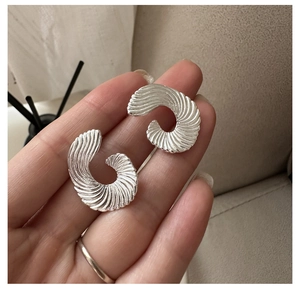 Macro detail of S925 silver fan-shaped C-hoop earrings with spiral textured finish