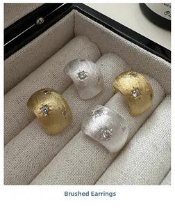 Close-up of brushed silver and gold star earrings with cubic zirconia in a jewelry box