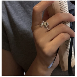 Detailed view of silver heart-shaped adjustable ring worn with artistic magazine prop