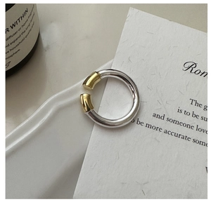 Détail de la bague en argent S925 avec contraste doré sur un plateau en céramique blanche