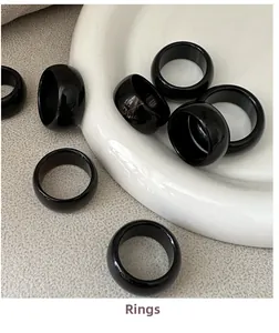 Close-up of eight glossy black onyx style rings on a minimalist ceramic tray