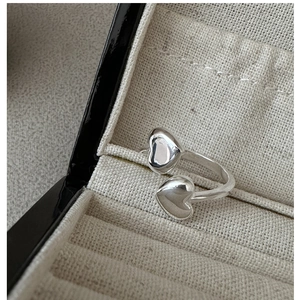 Macro shot of S925 sterling silver ring with double heart design on white fabric