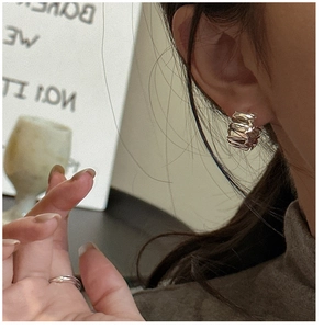 Gros plan de boucles d'oreilles argentées texturées et d'une bague polie minimaliste