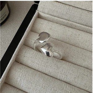 Close-up of polished S925 silver double heart open ring in a beige fabric jewelry box