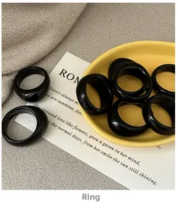 Polished black agate resin rings displayed on a minimalist yellow ceramic tray