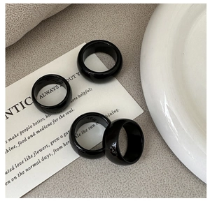 Detailed view of four minimalist black glossy rings displayed on minimalist cards