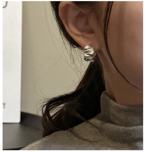 Détail macro de créoles en argent S925 avec texture métallique plissée irrégulière