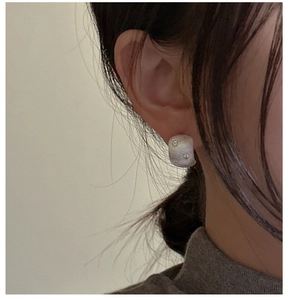 Detail of brushed S925 silver star earring with tiny inlaid zircons on a model's ear