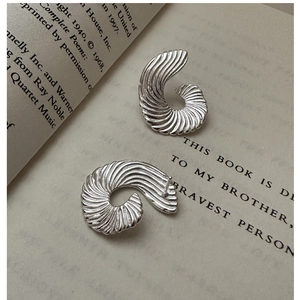 Macro shot of silver fan-shaped spiral earrings on an open book with elegant textures
