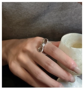 Close-up of a minimalist S925 sterling silver bow ring on a finger with a matte cup