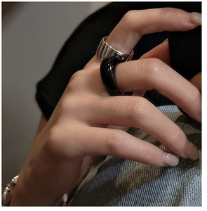 Close-up of minimalist silver metal ring and black resin ring set worn by a model