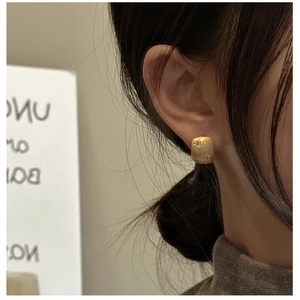 Detail of gold star earring with matte texture and small zircons worn by model