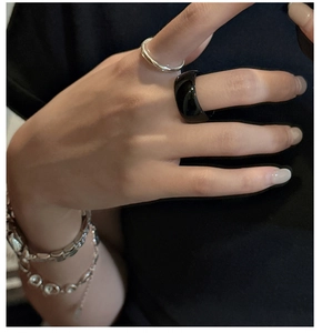 Detailed view of black agate ring and silver bracelets on model hand for a minimalist look