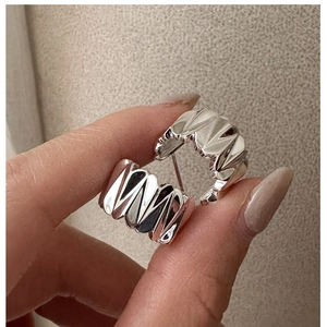 Gros plan de boucles d'oreilles créoles en argent S925 avec une texture ondulée unique