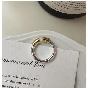 Vue macro d'une bague en argent S925 minimaliste avec embouts dorés sur une carte