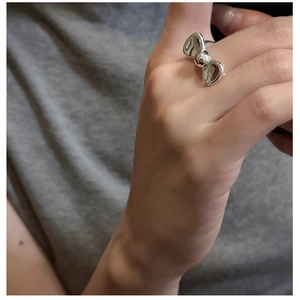 Detailed view of a silver bow-knot ring in polished S925 sterling silver on a finger