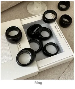Close-up of glossy black wide resin rings arranged in a minimalist jewelry display box