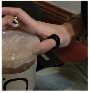 Minimalist silver wide round ring and chunky black resin ring worn in a stylish street style