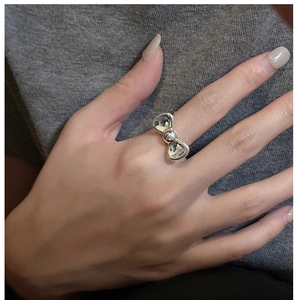 Detail view of a silver bow-shaped ring in polished metal worn by a model on index finger