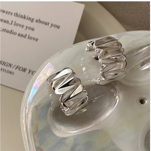 Détail des boucles d'oreilles S925 en argent texturé sur un plateau en céramique