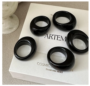 Set of five chunky black resin rings with polished finish displayed on minimalist packaging