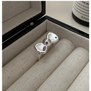 Macro shot of silver bow ring set in a grey velvet jewelry box with polished mirror finish