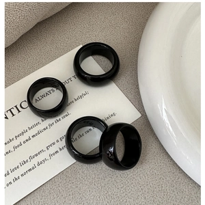 Top view of four minimalist black onyx style resin rings on white decorative card