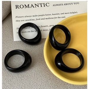Macro detail of high-gloss black resin rings with irregular design on minimalist decor