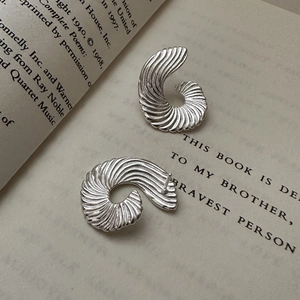Minimalist S925 sterling silver spiral fan-shaped earrings on a vintage book page