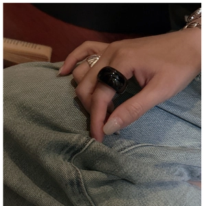 Detail of a minimalist wide black agate resin ring with high glossy finish on denim background