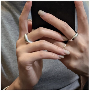 Detail showing a minimalist set of three polished silver rings worn on fingers