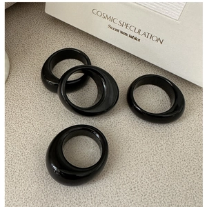 Minimalist glossy black wide band resin rings on a modern aesthetic grey background