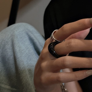 Set of minimalist black resin and silver engraved metal rings worn by a model