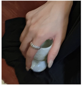 Detail of a polished S925 sterling silver croissant ring on a finger holding a cup