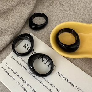 Chunky black resin dome ring set with minimalist polished finish on a ceramic tray