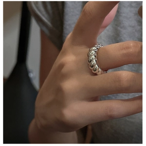 Macro detail of silver croissant ring with textured spiral design worn on finger