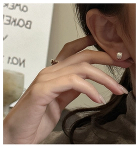 Detail shot of triple-layer texture silver stud earring on ear with warm aesthetic
